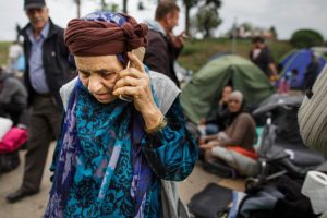 SID, SERBIA - SEPTEMBER 22: A migrant speaks on a smartphone as she and other migrants wait in a holding area just metres across from the Croatian border after walking the last few kilometres from Serbia to Croatia on September 22, 2015 in Sid, Serbia. Thousands of migrants have arrived in Austria over the weekend with more en-route from Hungary, Croatia and Slovenia. Politicians across the European Union are to hold meetings on the refugee crisis with EU interior ministers meeting tomorrow and EU leaders attending an extraordinary summit on September 23. (Photo by Carsten Koall/Getty Images)